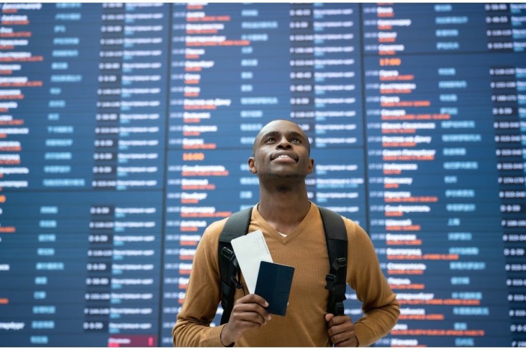 Homme devant un panneau d'aéroport.