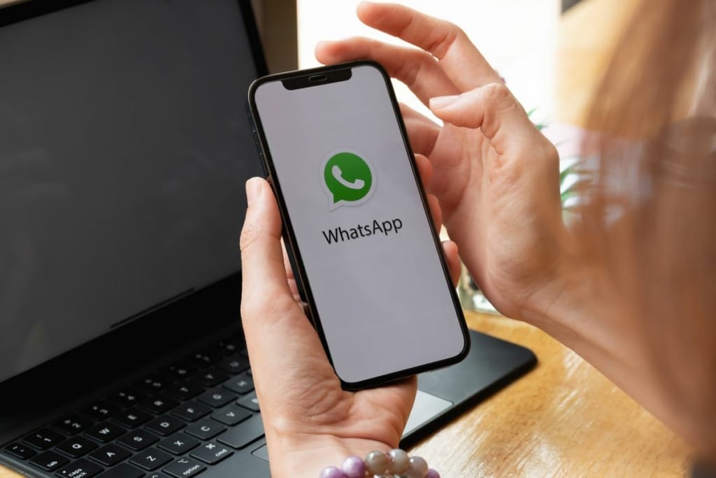 Personne tenant un smartphone et ouvrant l'application Whatsapp