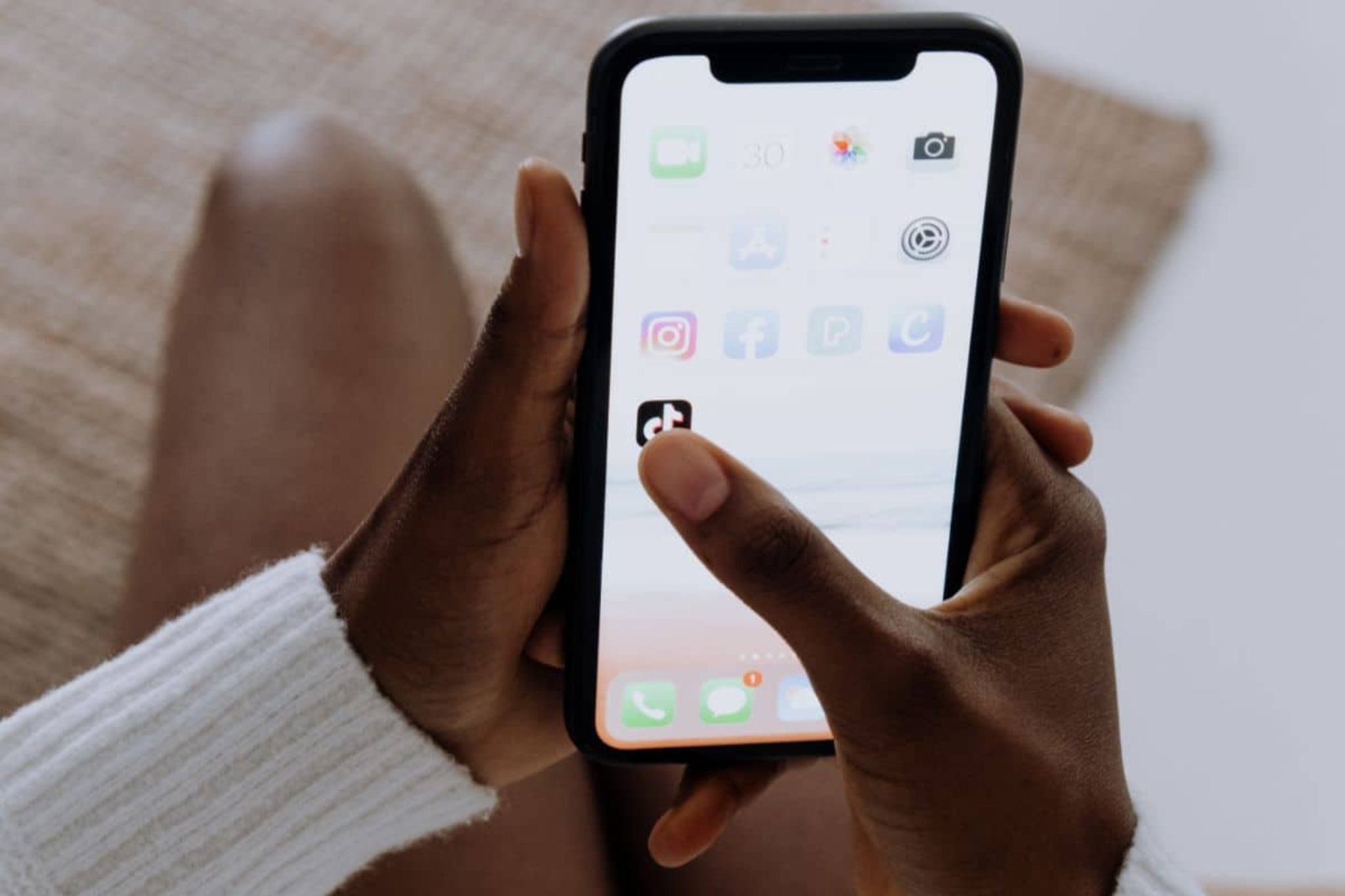 Une jeune femme tenant un iPhone et prête à faire une recherche depuis l'application TikTok