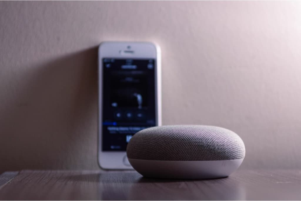 Enceinte Google Home mini placée devant un smartphone