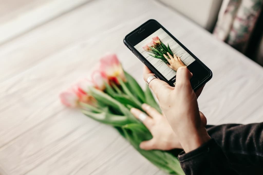 Une personne prend un bouquet de fleurs en photo avec son téléphone