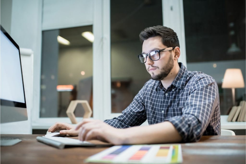 Un homme à lunettes travaille sur ordinateur.