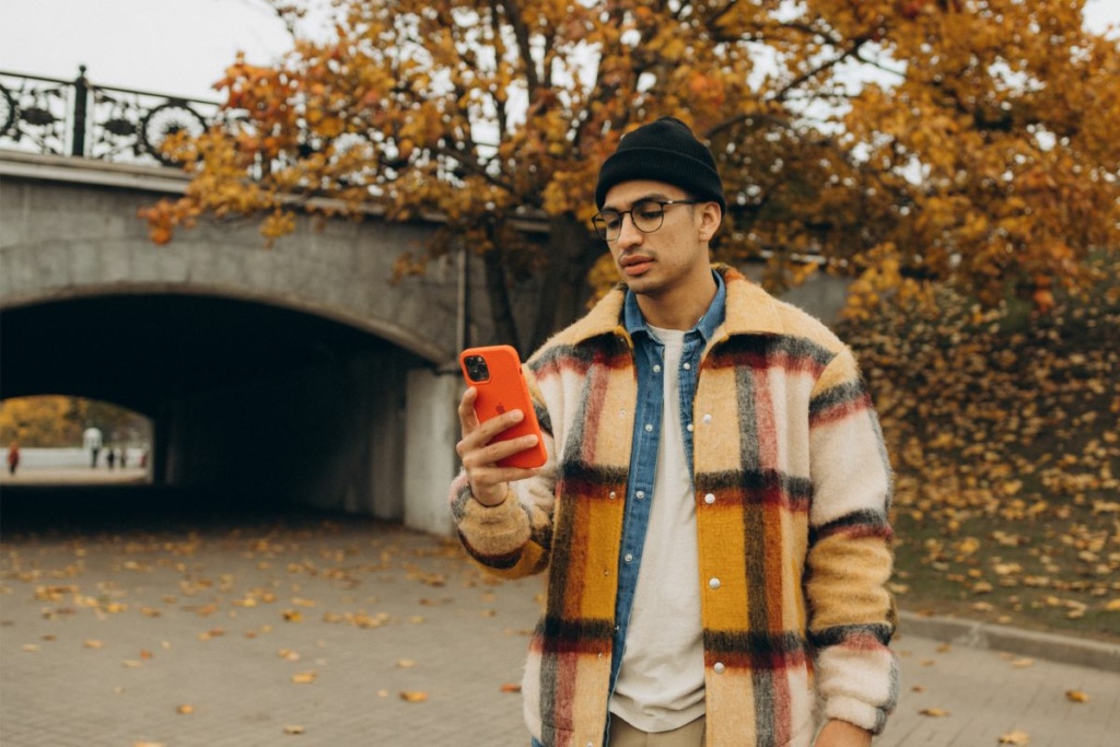 Un homme dans un parc utilise un Iphone.