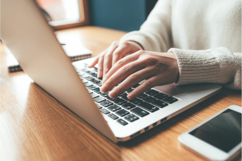 Des mains tapent sur un clavier d'ordinateur.