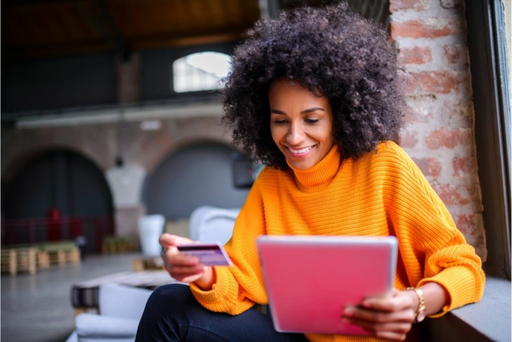 Une femme tient une tablette et une carte bancaire.